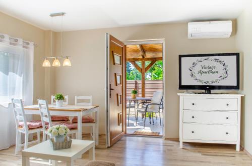 a living room with a dining table and a television at Vintage apartman in Mezőkövesd