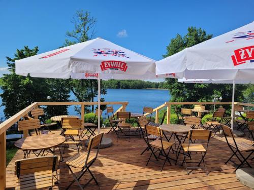 a deck with tables and chairs and umbrellas at Hotel Mazuria Country & SPA in Mrągowo