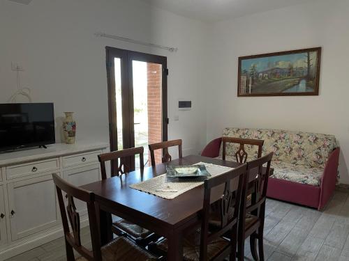a dining room with a table and a couch at S’apposentu in Solinas