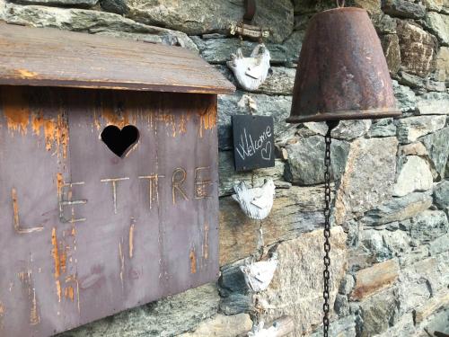 a metal sign on a stone wall with a bell at Au Rascard in Brusson
