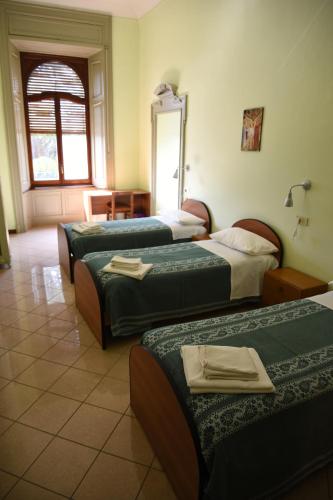 a hotel room with three beds and a mirror at Villa San Giuseppe in Brescia