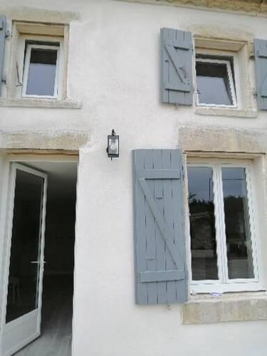 a white building with blue shutters and a door at Maison de campagne "Beun'aise" in Val-du-Mignon