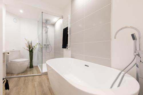 La salle de bains blanche est pourvue d'une baignoire et de toilettes. dans l'établissement HeavnStay Suite Cannes Centre I, à Cannes