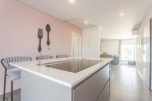 a white kitchen with a counter and a kitchen island at Apartamento T2 Tin Tin in Nazaré