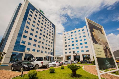 Bourbon Ponta Grossa Convention Hotel في بونتا غروسا: مبنيان طويلان مع سيارات متوقفة في موقف للسيارات