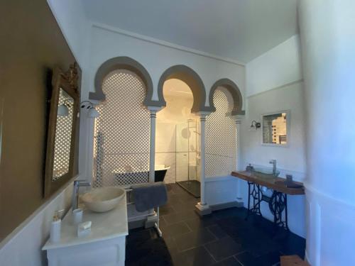 a bathroom with a sink and two arched windows at Eco Logis de Chantegrolle in Champagne-Mouton