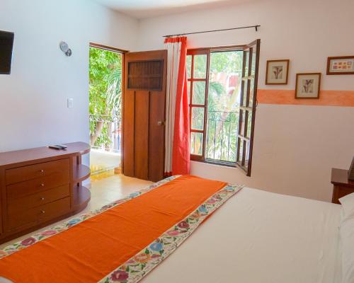 a bedroom with a bed and a dresser and a window at Hotel Casa de las Flores in Playa del Carmen