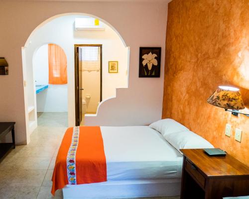 a bedroom with a bed and a table with a lamp at Hotel Casa de las Flores in Playa del Carmen