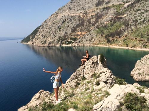 two women standing on the edge of a mountain near the water at Hostel Dalmatia in Marusici 