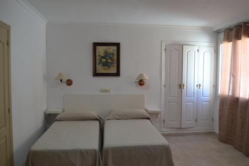 two beds in a room with white walls at Hotel Miramar in La Línea de la Concepción