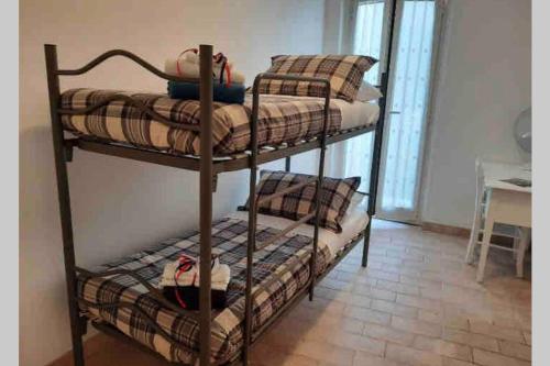 three bunk beds in a room with a table at Casa Flea - Holiday apartment with 2 bedrooms in Gualdo Tadino