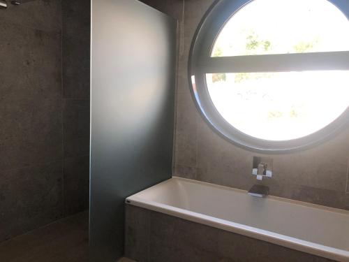 a bathroom with a tub and a round window at Luxury Zen in Châteauneuf