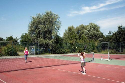 two young girls playing tennis on a tennis court at Vakantiehuis 6pers op park 't Broeckhuys in Ewijk groot Zwemplas in het land van Maas & Waal niet voor arbeidsmigranten in Ewijk