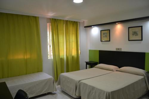 a bedroom with two beds and green curtains at Hotel Miramar in La Línea de la Concepción