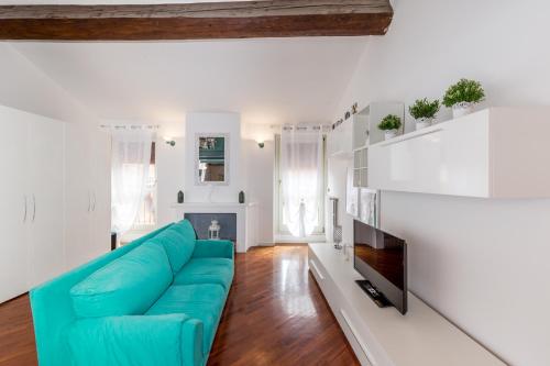 sala de estar con sofá azul y TV en Maison Contrari en Ferrara