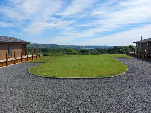 a large field of grass next to a house at Luxury family Beechwood lodge with hot tub in Lochwinnoch