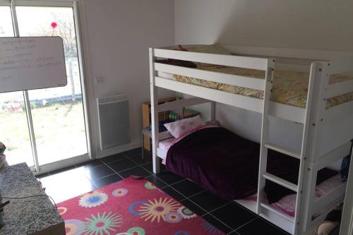 une chambre avec deux lits superposés et un tapis dans l'établissement Maison Girolle, à Vendays-Montalivet