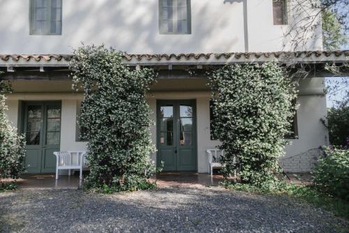 a white house with a green door and two chairs at Estancia La Paz Hotel in Ascochinga