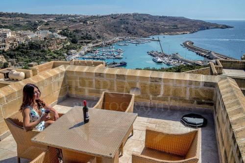 a woman sitting at a table with a bottle of wine at Fort Chambray Harbor Breeze in Għajnsielem