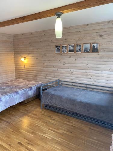two beds in a room with wooden walls at Pervalkos Dainava in Pervalka