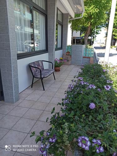 a bench sitting outside of a building with purple flowers at Hotel Danubio in Bellaria-Igea Marina