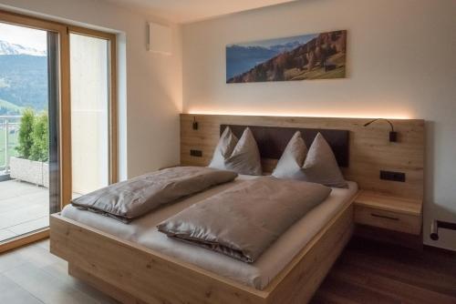 1 dormitorio con cama de madera y ventana grande en Jaufnerhof en Mareta