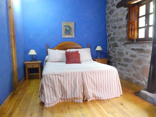 1 dormitorio con 1 cama con paredes azules y suelo de madera en Cabaña pasiega Las Lugas, en Liérganes
