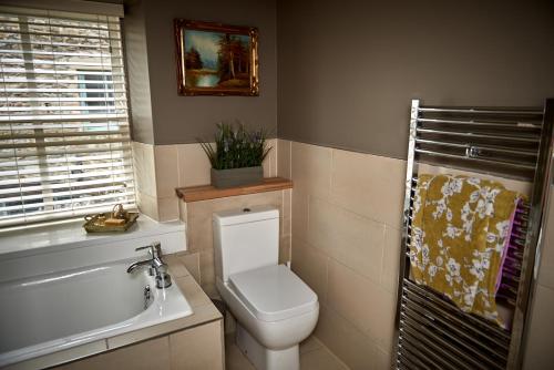 a bathroom with a toilet and a tub and a sink at Maltings Cottage in Barnard Castle