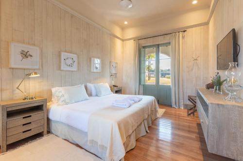 a bedroom with a large white bed and a television at Estancia La Paz Hotel in Ascochinga