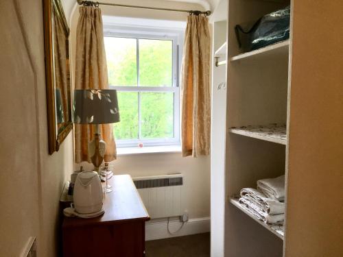 a room with a window and a table with a microwave at Rosalie Guest House in Penzance