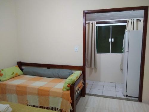 una piccola stanza con un letto e un frigorifero di Casa da Celia 02 ad Arraial do Cabo