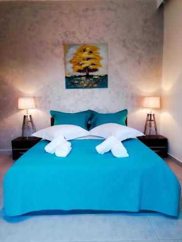 a blue bed with two white towels on it at Magdalena Seaside Apartments in Nea Roda