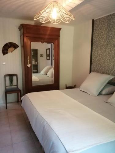 - une chambre avec un grand lit blanc et un miroir dans l'établissement La Parenthèse, à Saint-Étienne-du-Bois