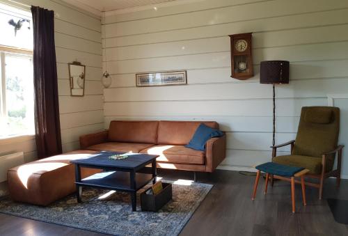 a living room with a couch and a table and a clock at Øygarden i Heggjabygda in Nordfjordeid