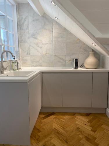 a kitchen with white cabinets and a sink and a window at The Beach Retreat Whitstable in Kent