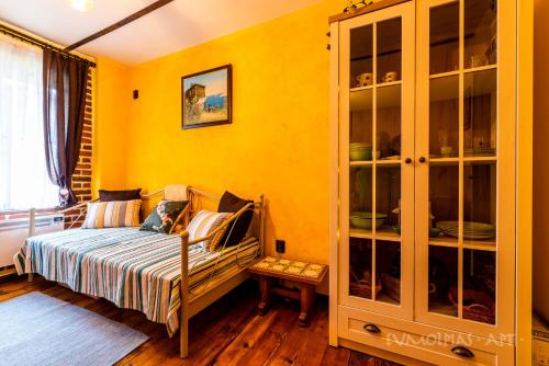 een gele kamer met een bed en een kast bij Art apartment EVMOLPIAS near Roman stadium in Plovdiv