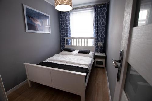 a small bed in a room with a window at Apartament IKAR przy morzu w kompleksie LAOLA in Pobierowo