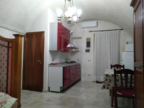 una cucina con armadi rossi e frigorifero bianco di Casa Charme Rotonda a Mottola