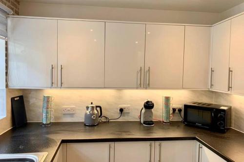 a kitchen with white cabinets and a microwave at Durham House - Fantastic Location and Great Price in Scarborough in Scarborough