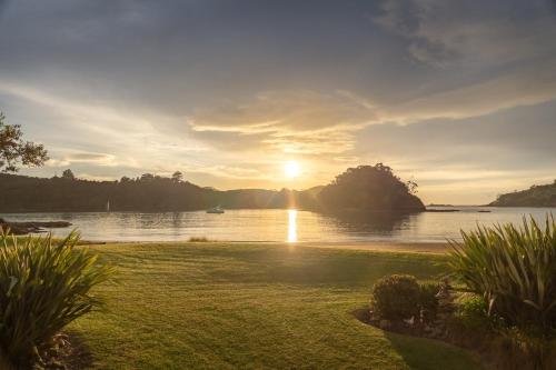 a view of a river with the sun setting over the water at Absolute Beach front-Tutukaka Harbour in Tutukaka