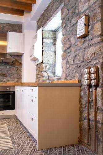 a kitchen with white cabinets and a stone wall at Samaradiko in Kondiás