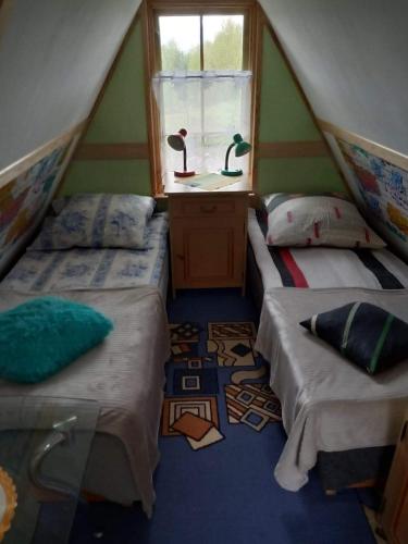 two beds in a room with a window at Domek pod lasem in Maniowy
