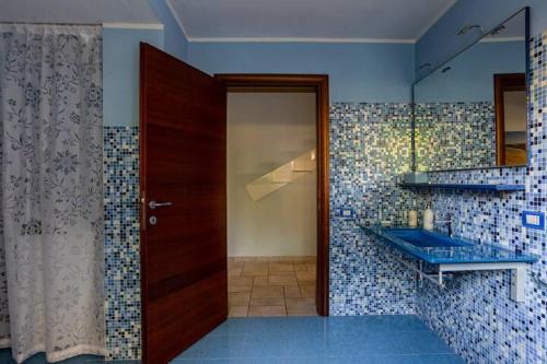 un bagno con porta in legno e lavandino blu di Appartamento Fronte Mare - parcheggio privato a Pescara