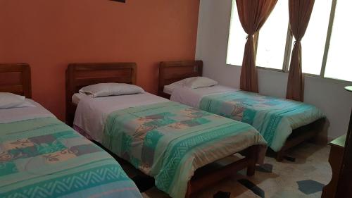 two beds in a room with two windows at Balneario Chorillano in Villavicencio