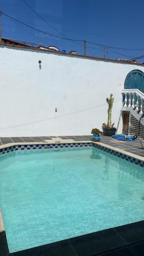 a large swimming pool in front of a white wall at Ocean Front Antique House, Private Beach! in Rosarito