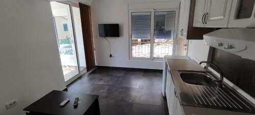a small white kitchen with a table and a window at Zoran Apartments in Sveti Stefan
