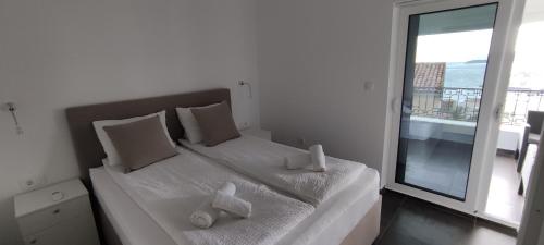 a bedroom with a white bed with a large window at Zoran Apartments in Sveti Stefan