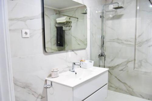 a white bathroom with a sink and a shower at The Light House II, with rooftop and parking in Nazaré
