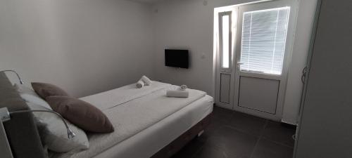 a bedroom with a bed with a window and a television at Zoran Apartments in Sveti Stefan