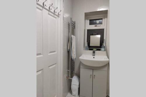 ein weißes Badezimmer mit einem Waschbecken und einem Spiegel in der Unterkunft Luxury apartment in Birmingham with free parking. in Birmingham